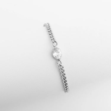 Silver chain earring with a clear gemstone on a light gray background