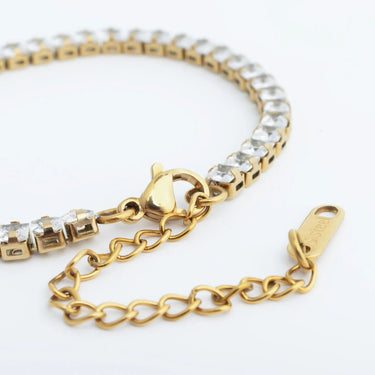 Gold bracelet with heart clasp on a white background