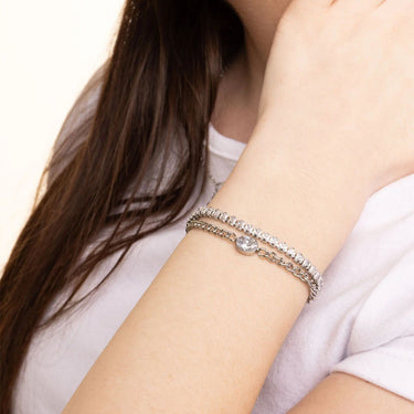 Close-up of a person wearing a silver bracelet on a plain background
