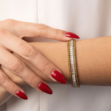 Close-up of a hand with red nail polish and a gold bracelet on a white background
