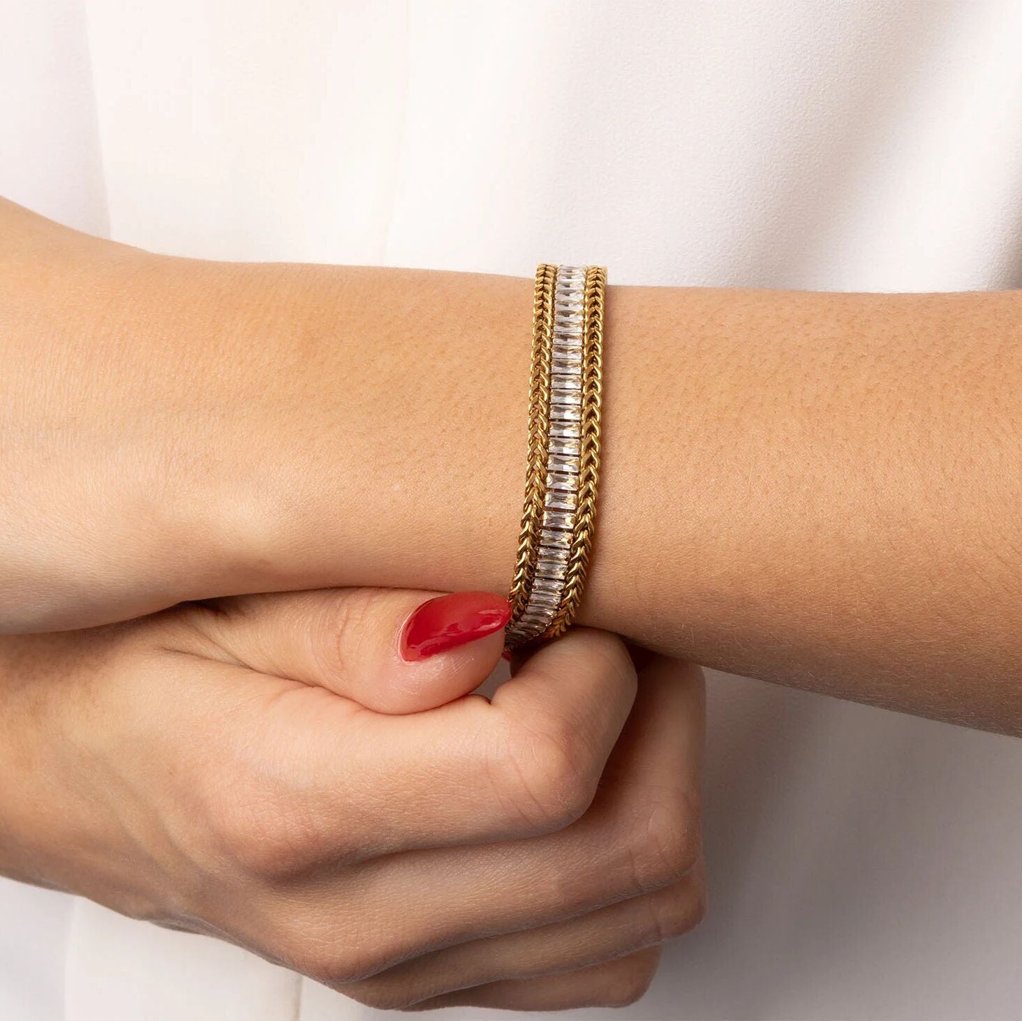 Gold bracelet on a wrist with a neutral background