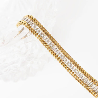 Gold bracelet with clear gemstones on a white background