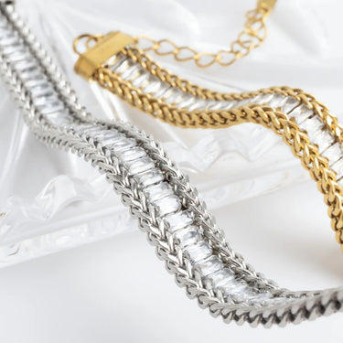 Two gold and silver chain necklaces on a white fabric background