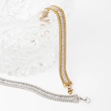 Gold and silver chain bracelets on a textured white surface