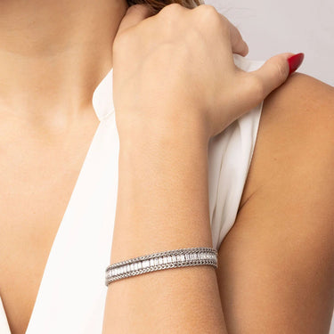 Silver bracelet on a wrist with a neutral background