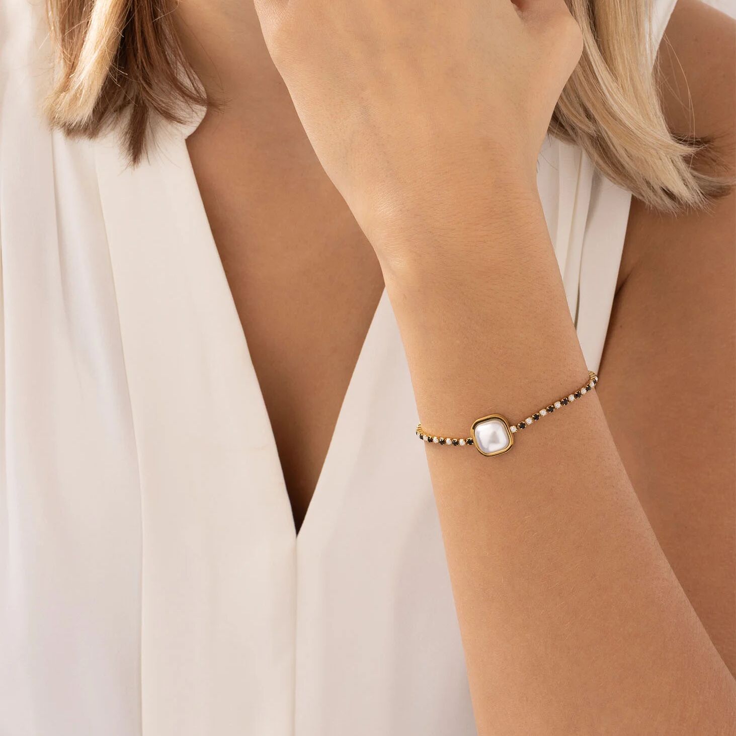 Close-up of a woman's wrist wearing a delicate bracelet with a pearl-like stone.