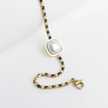 Gold necklace with a large pearl pendant on a light gray background