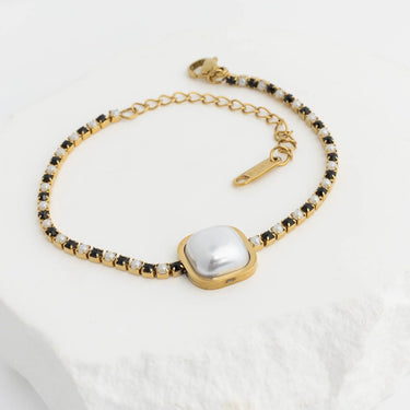 Gold bracelet with a central pearl on a white background