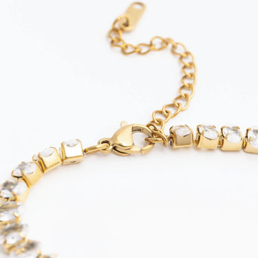Gold bracelet with clear gemstones on a white background