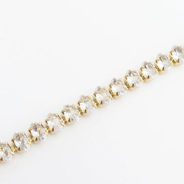 Gold bracelet with clear gemstones on a light gray background