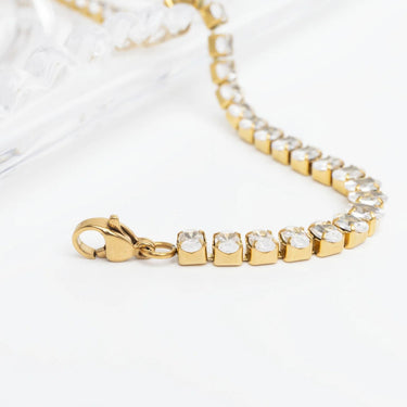 Gold bracelet with clear stones on a white background