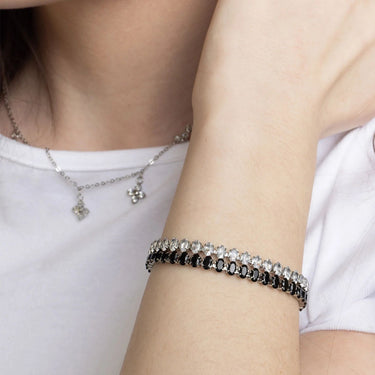 Close-up of a person wearing a silver bracelet and necklace on a white background