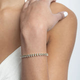 Silver bracelet on a wrist with a neutral background