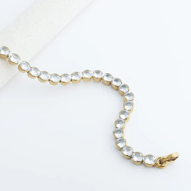 Gold bracelet with clear stones on a white background