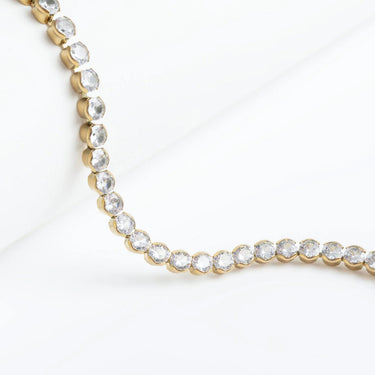 Gold necklace with clear stones on a white background