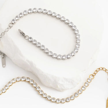 Two crystal-encrusted chains, one gold and one silver, on a white background.