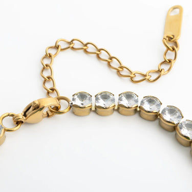 Gold bracelet with clear gemstones on a white background
