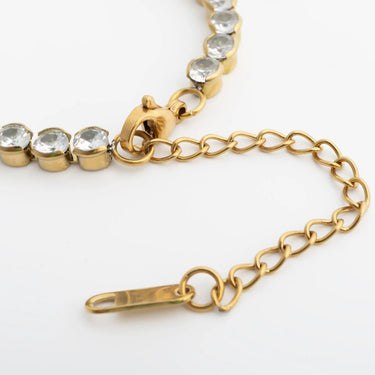 Gold bracelet with clear gemstones on a white background