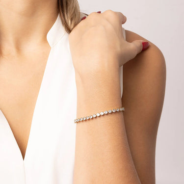 Close-up of a woman's arm wearing a diamond bracelet on a plain background