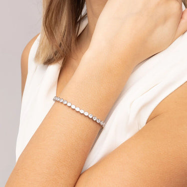 Silver bracelet on a person's wrist with a plain background