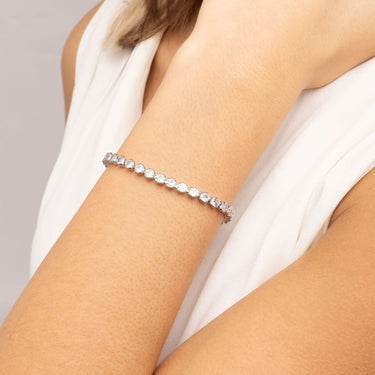 Silver bracelet on a person's wrist with a plain background