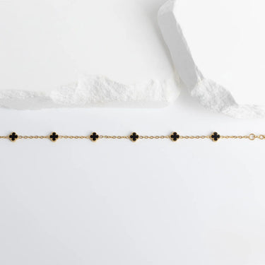 Gold Small Floral Motif Bracelet  with black clover-shaped charms on a white background