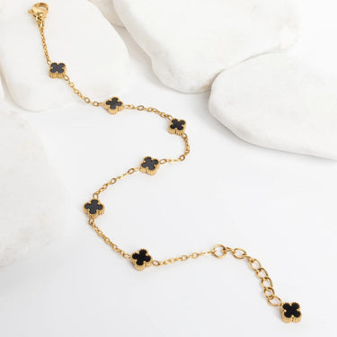Gold Small Floral Motif Bracelet  with black flower-shaped charms on a white surface