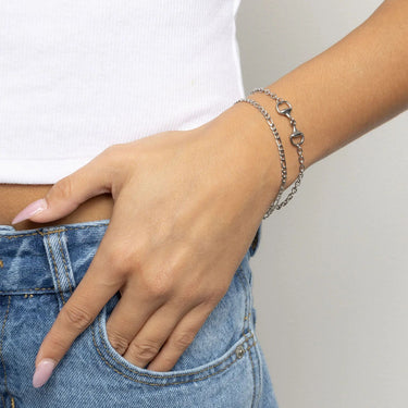 Hand wearing a silver Horsebit Bracelet with a plain background