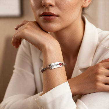 Person wearing a bracelet with 'AUTISM' on it, sitting in a neutral setting.