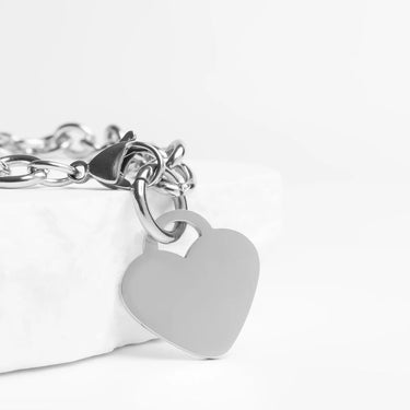 Silver bracelet with a heart-shaped tag on a white background