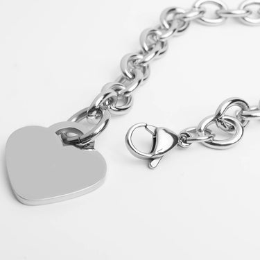 Silver bracelet with a heart-shaped tag on a white background