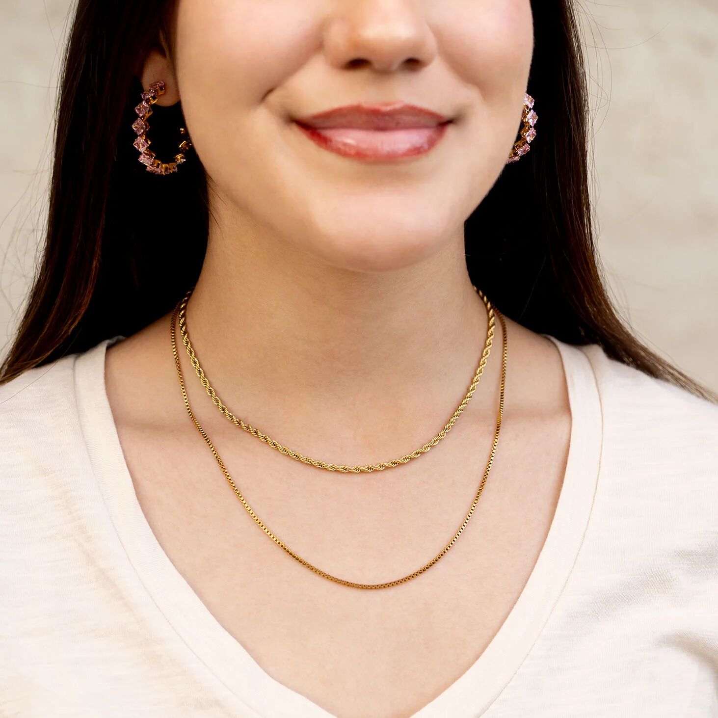 Woman wearing a gold necklace with a neutral background
