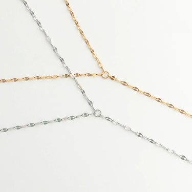 Two gold and silver Full Body Chain Lip Chain intersecting on a light gray background