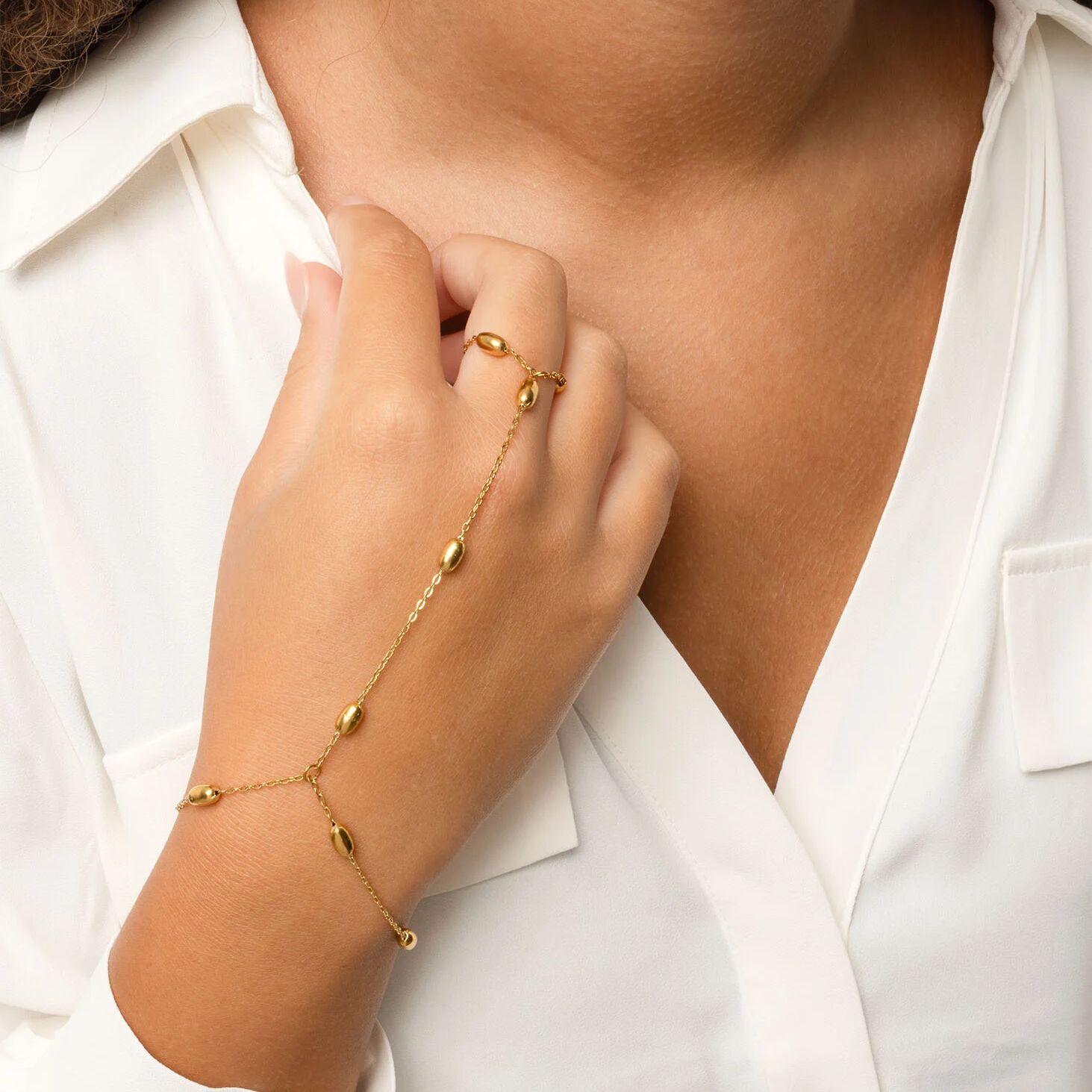 Gold Statement Bead Hand Chain  on a person's wrist with a white shirt background