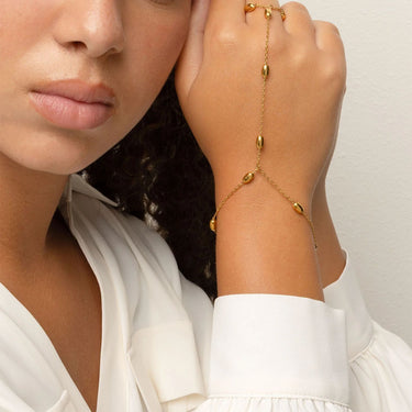 Woman wearing a gold Statement Bead Hand Chain on a plain background