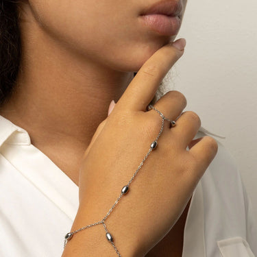 Close-up of a hand wearing a delicate silver Statement Bead Hand Chain with small beads.
