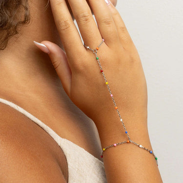 Hand wearing a silver Multi Color Hand Chain on a neutral background