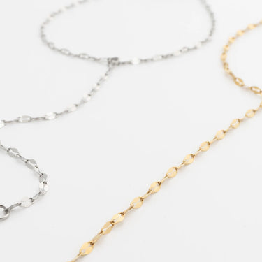 Two gold and silver Lip Hand Chain on a light gray background