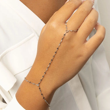 Hand wearing a delicate silver Lip Hand Chain on a white background