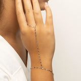 Hand wearing a delicate silver Lip Hand Chain on a plain background