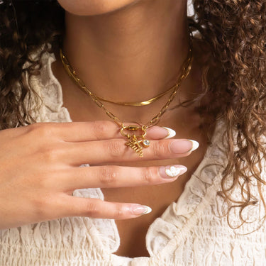 Close-up of a woman wearing gold jewelry with a neutral background