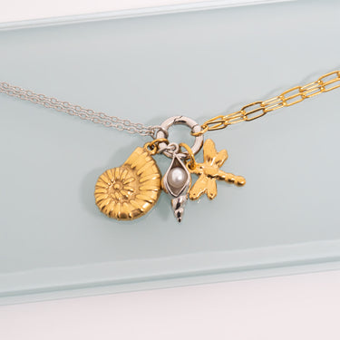 Necklace with gold and silver charms on a light gray background