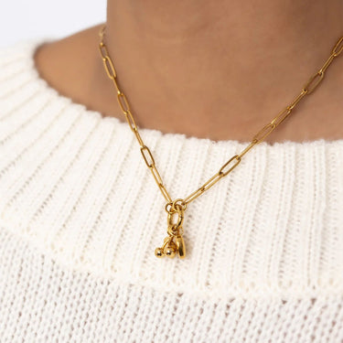 Gold chain necklace with a small pendant on a white sweater