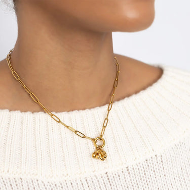 Gold chain necklace with a small pendant worn by a person in a white sweater.