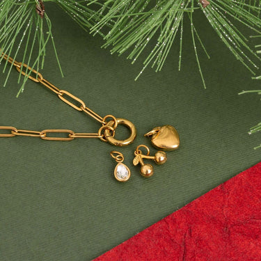 Gold jewelry set including a necklace, earrings, and heart-shaped pendant on a green surface with red fabric underneath.