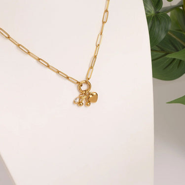 Gold necklace with a heart-shaped pendant on a light background