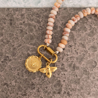 Beaded bracelet with gold charm on a marble surface
