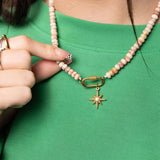 Necklace with a star-shaped pendant being adjusted on a green shirt