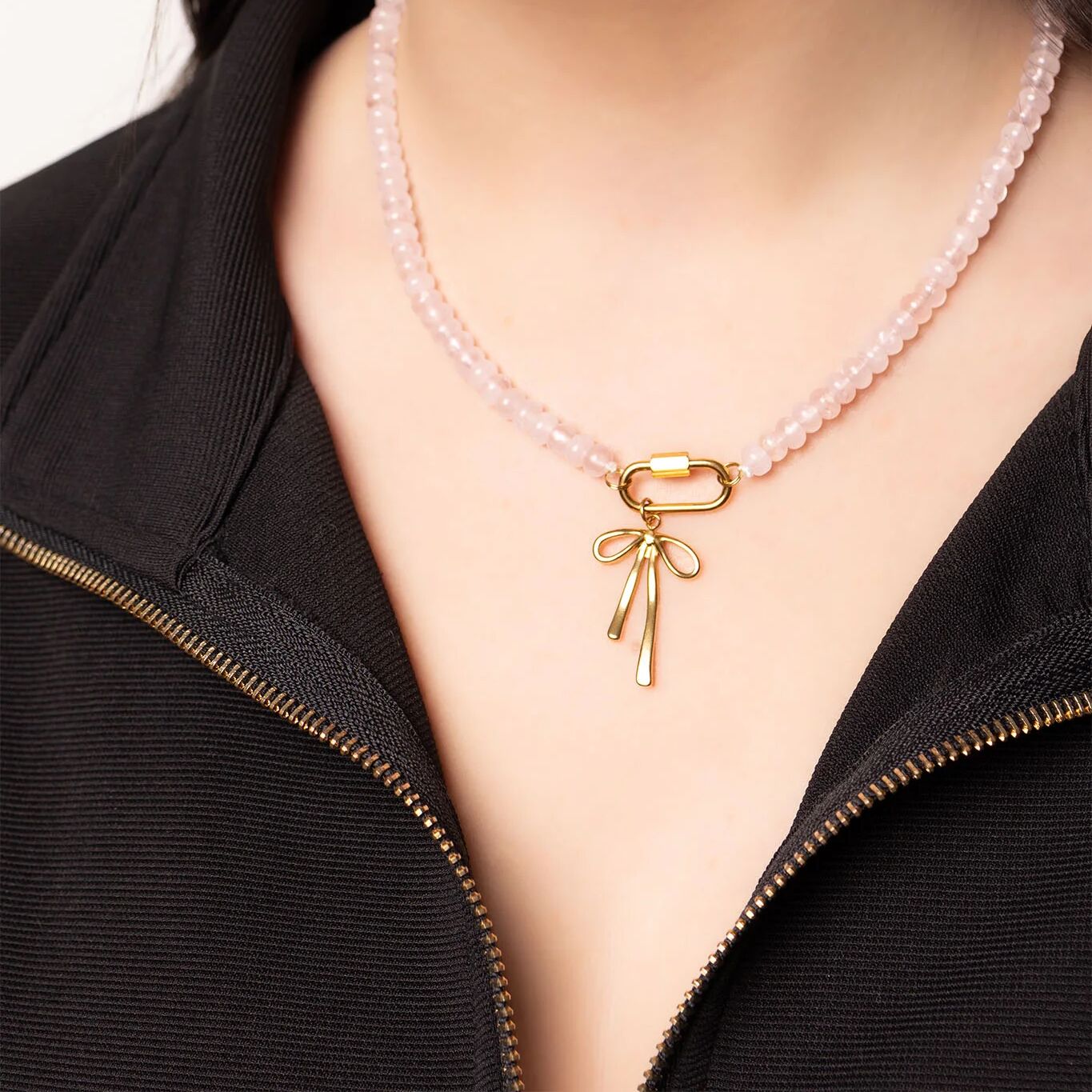 Necklace with a gold bow pendant on a girl wearing a black top.