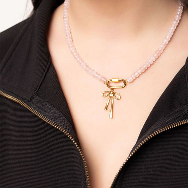 Necklace with a gold bow pendant on a girl wearing a black top.